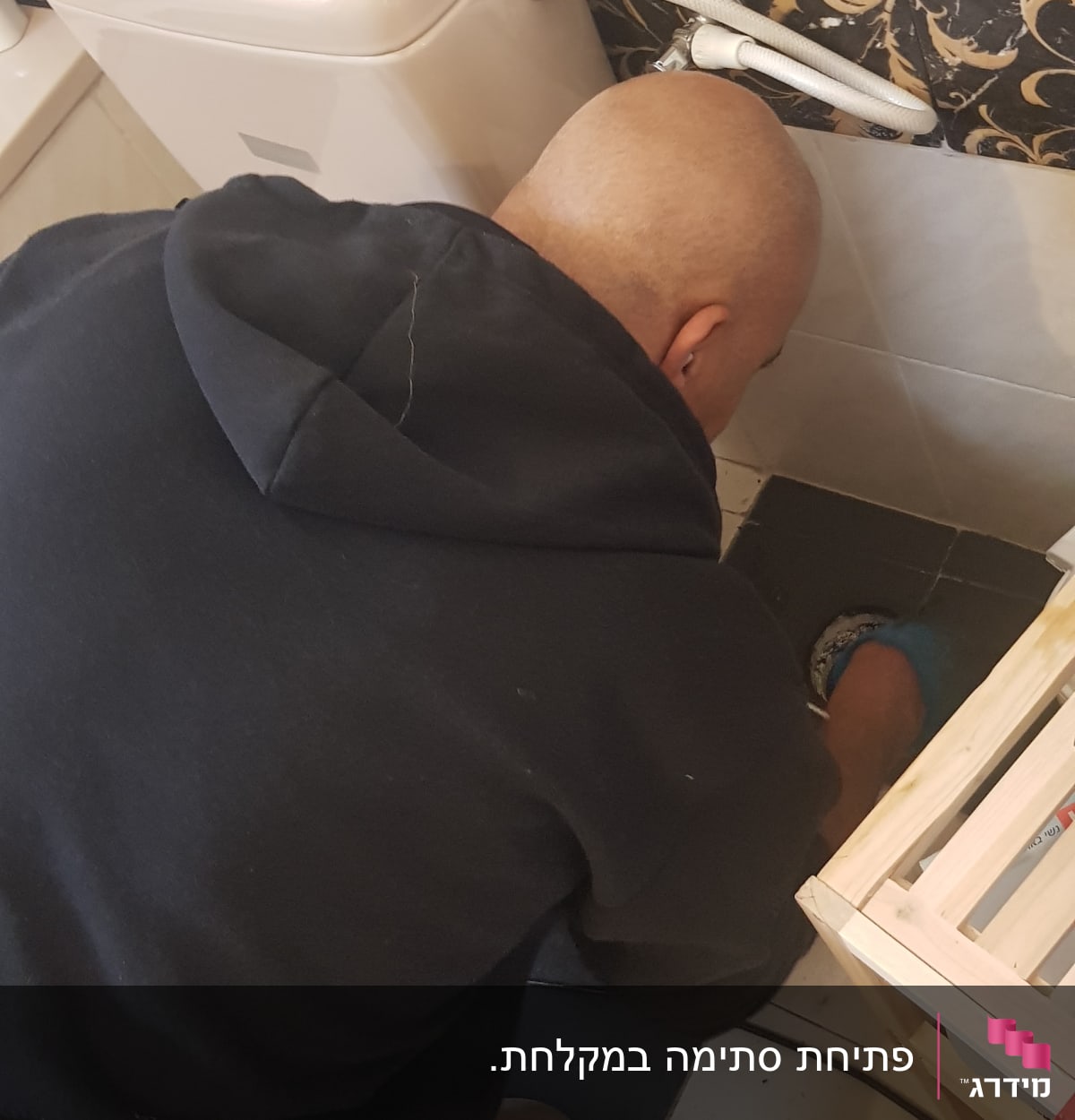 אדם עובד על צנרת ליד אסלה בשירותים